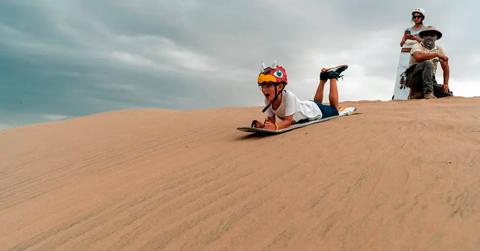 Boy sandboarding in the Huacachina dunes in Ica