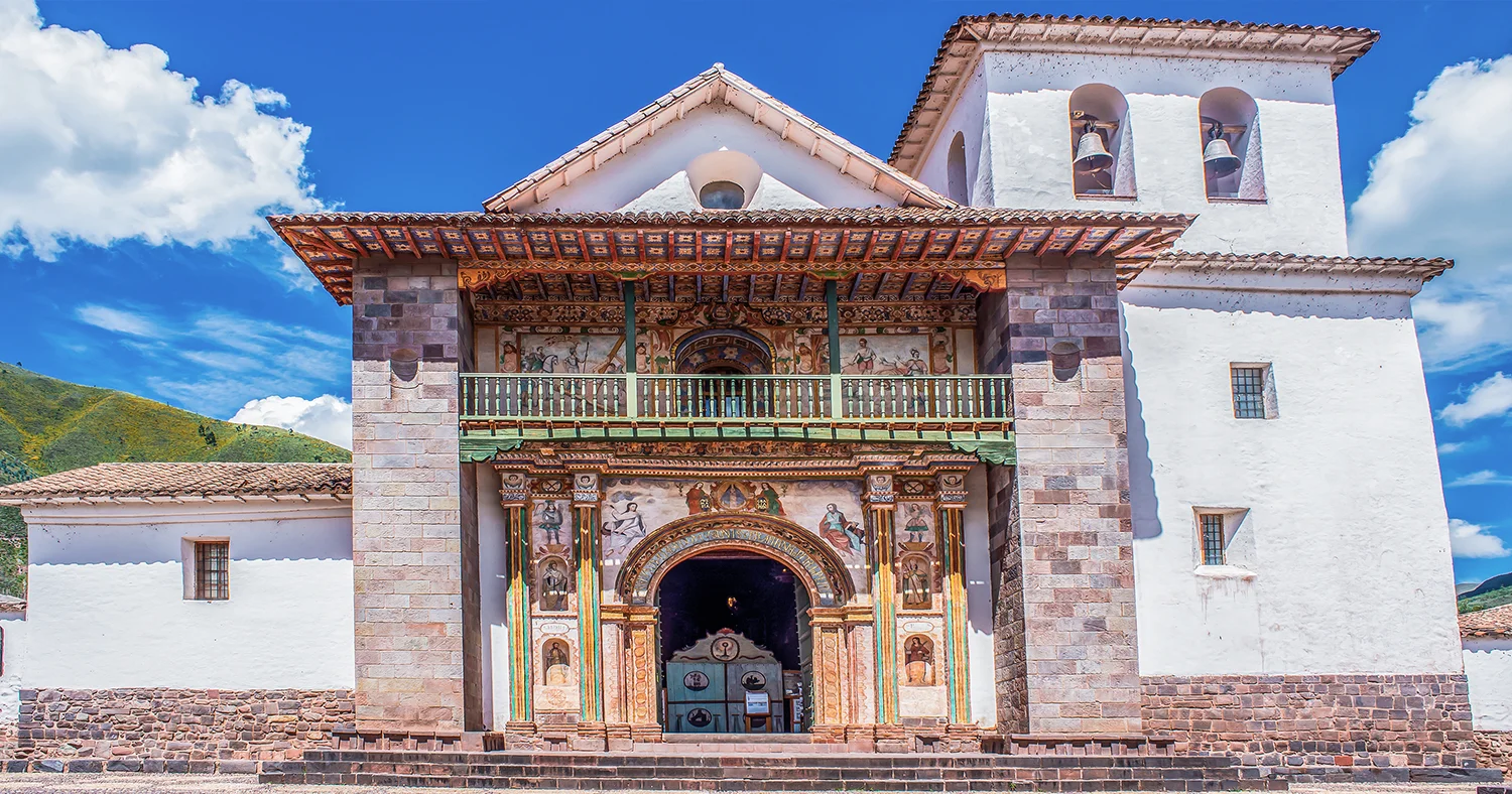 Colonial facade of Andahuaylillas Church with painted decorations and a bell tower in Cusco, Peru
