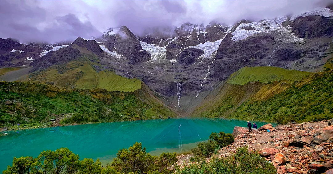 Hikers descending a mountain trail with panoramic views of the Peruvian Andes