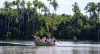 World Wildlife Day in Peru – guided boat tour through the Amazon rainforest with travelers observing wildlife along a palm-lined river.